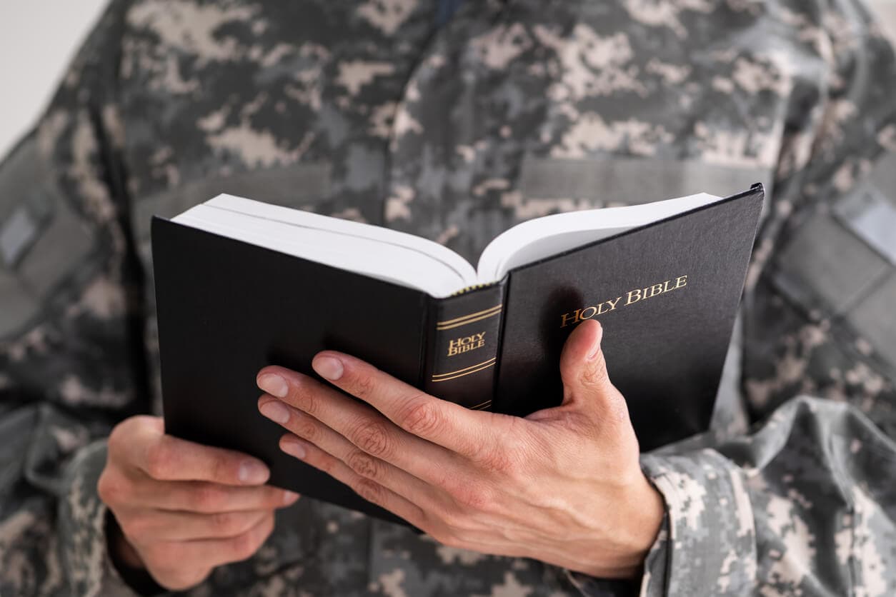Person in military uniform holding an open Holy Bible.