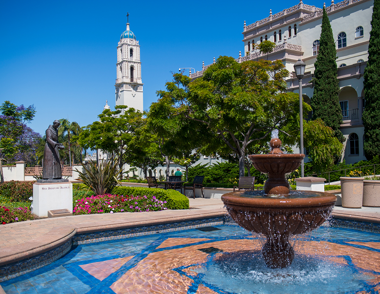 A courtyard with a decorative blue tile fountain, surrounded by trees and colonial architecture.