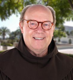 Smiling man with glasses wearing a black hoodie outdoors.