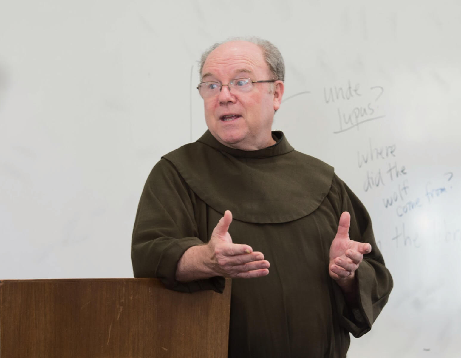 pastor speaking by a podium in a classroom.