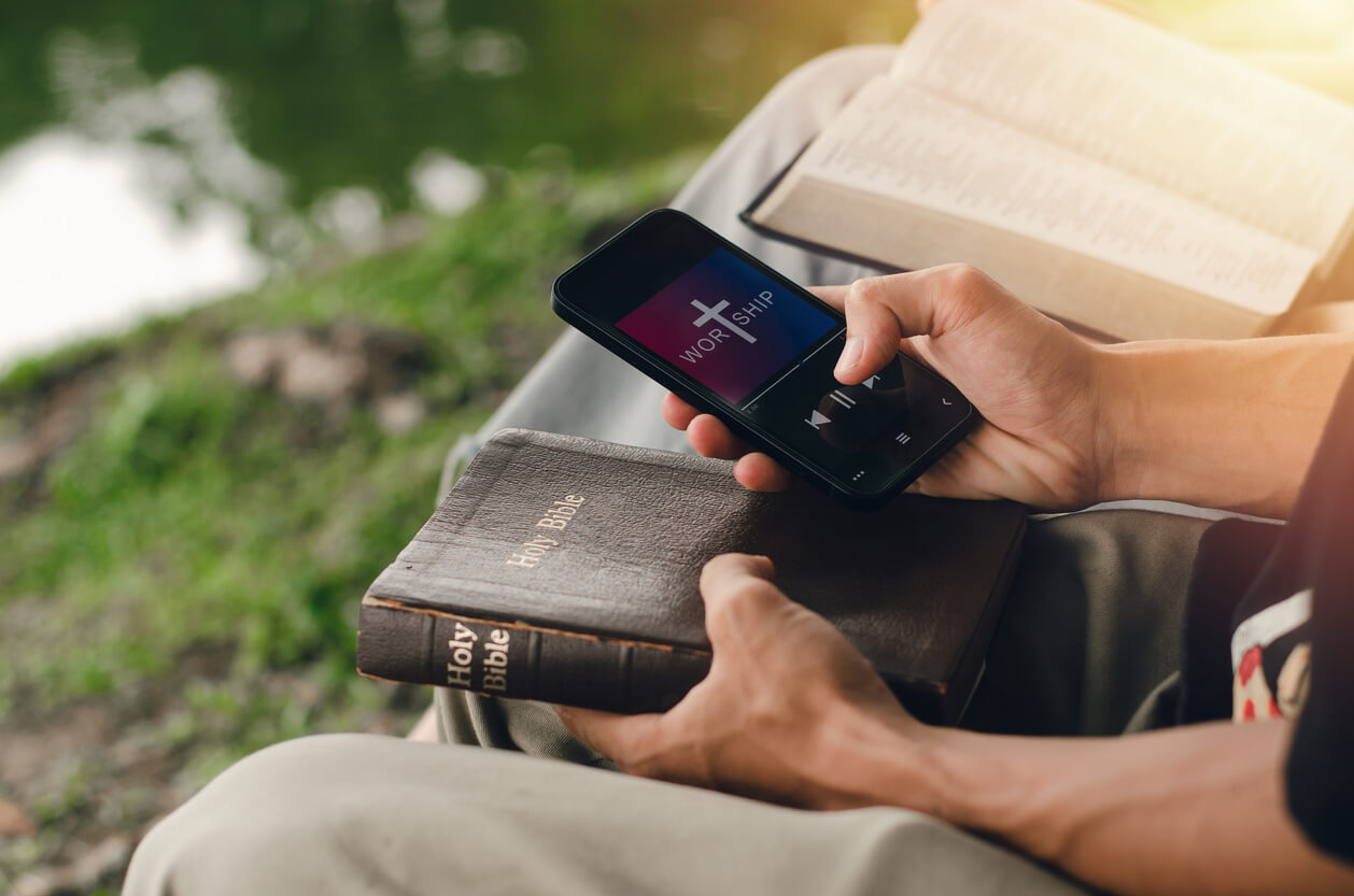 Two young people searching the Bible on their smartphones.